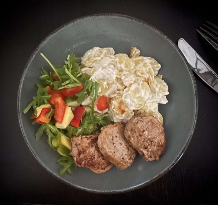 Fläskfilé och potatisgratäng med sallad innehållande färsk mango, serverat på en grön tallrik.
