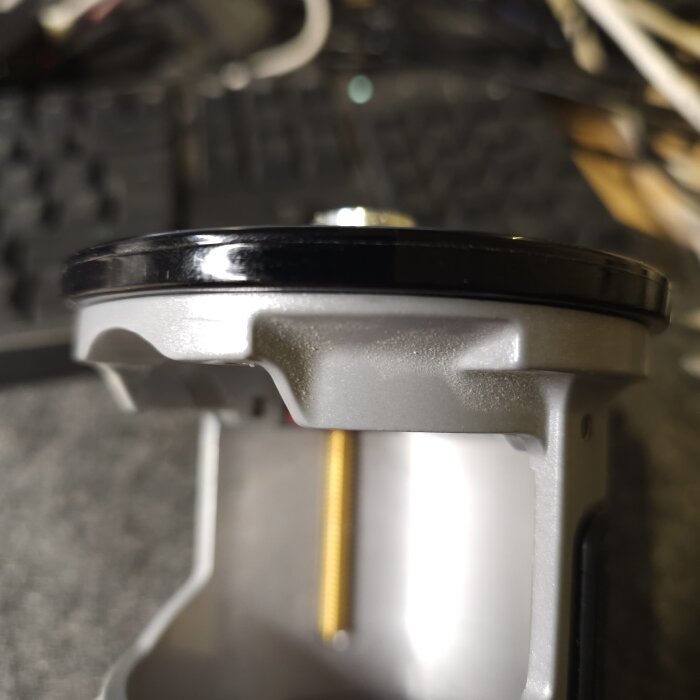 Närbild av en hylsa med fyra klackar som passar i gropar på basen, med en guldfärgad skruv synlig i bakgrunden.