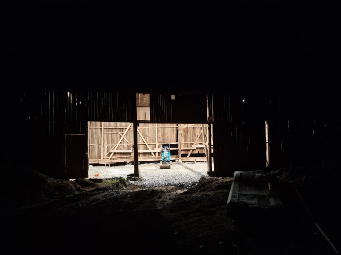En byggarbetsplats med upplyst område i mörker, byggbelysning syns tydligt i den skymda miljön.