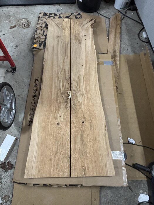 Gammal ekplanka ligger på kartong, redo att användas för att montera krokar i badrum enligt inlägget om renovering.