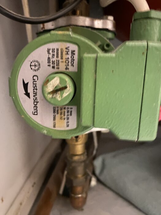 Grön Gustavsberg vattenpump, modell VHI 101(F4), med ledningar och rör i bakgrunden.