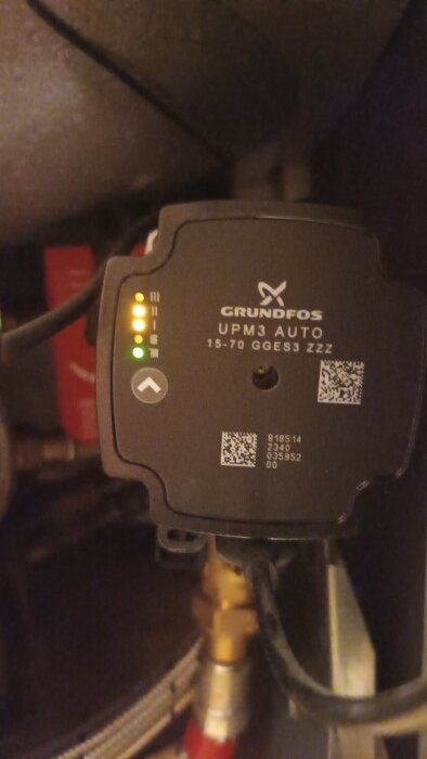 Cirkulationspump av märket Grundfos UPM3 Auto med indikatorlampor och QR-kod, del av ett värmesystem med pågående felsökning.
