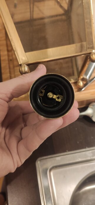 Hand som håller i en lamphållare, fokus på insidan där kontakter syns.