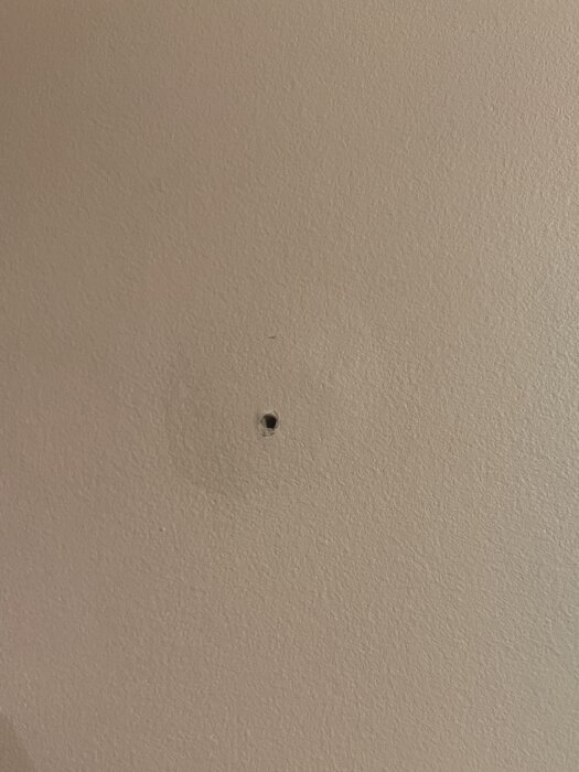 Hål med bubbla i betongvägg med beige yta i lägenhet från 50-talet.