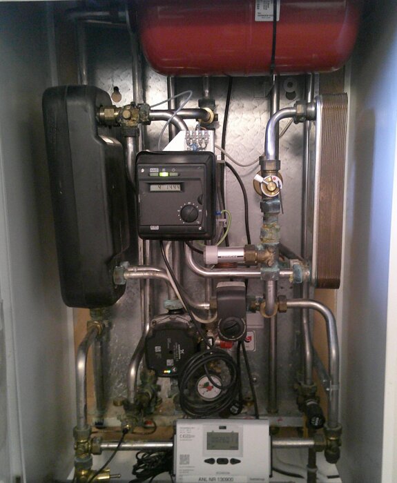 VVS-system i ett skåp med rör, ventiler och en kontrollpanel.