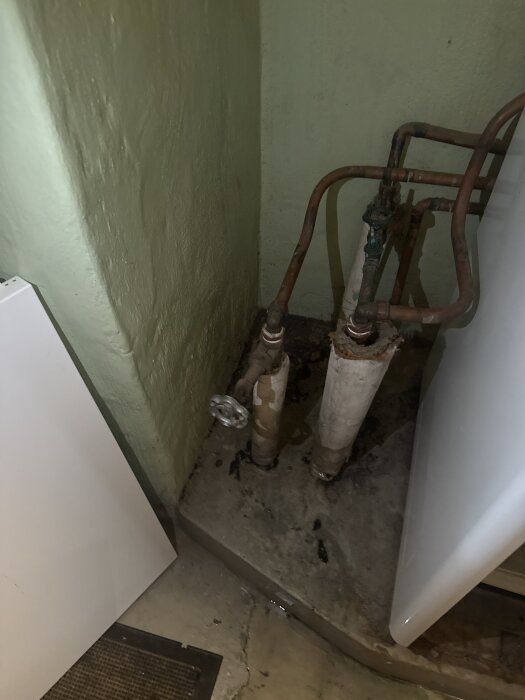 Rör och ventiler i ett trångt utrymme med gröna väggar, potentiellt kopplade till ett värmesystem i ett hus där elementen inte fungerar.