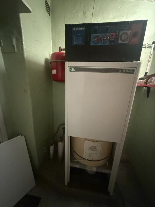 Värmepanna av märket CTC Safir i ett grönt rum, med röda och blå reglage.