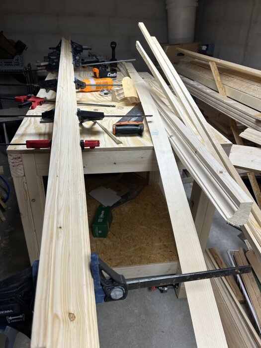 Brädor och verktyg på en arbetsbänk, del av projekt för att bygga om en blivande taklist eller krönlist.