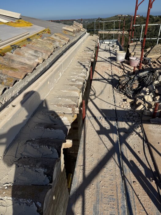 Tegelläggning på tak med byggnadsställningar och återbrukade tegelpannor för takutsprång.