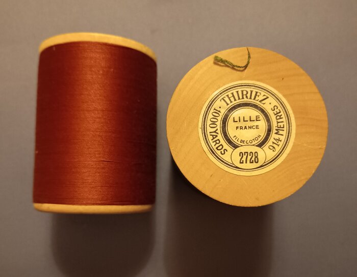 Äldre trådrullar i trä med etikett från Thiriez, visar 1000 yards stoppgarn. En rulle med brunt garn, etikett på den andra.