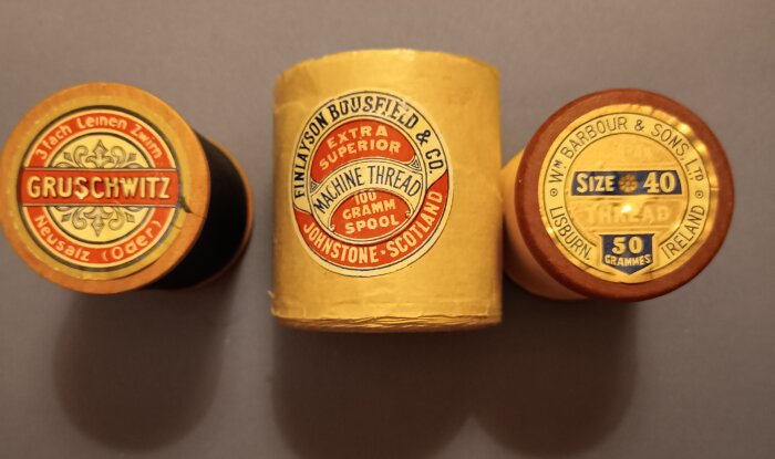 Äldre trådrullar i trä med etiketter, innehållande stoppgarn av nylon och perlon från olika tillverkare.