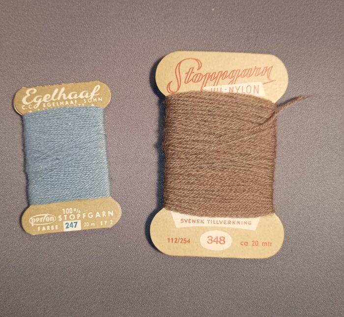 Äldre trådrullar i trä med blått garn av perlon och brunt garn av nylon, märkta med "Egelhaaf" och "Stoppgarn".