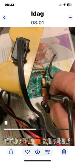 En hand håller en testprob mot ett kretskort som sitter ihop med ett guldfärgat Topcon Laser-batteri, med svarta kablar synliga.