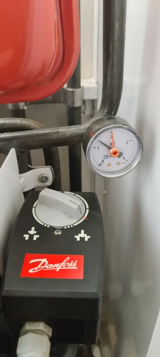 Danfoss styrventil med tryckmätare som visar cirka 1,5 bar, rör och en röd tank syns i bakgrunden.