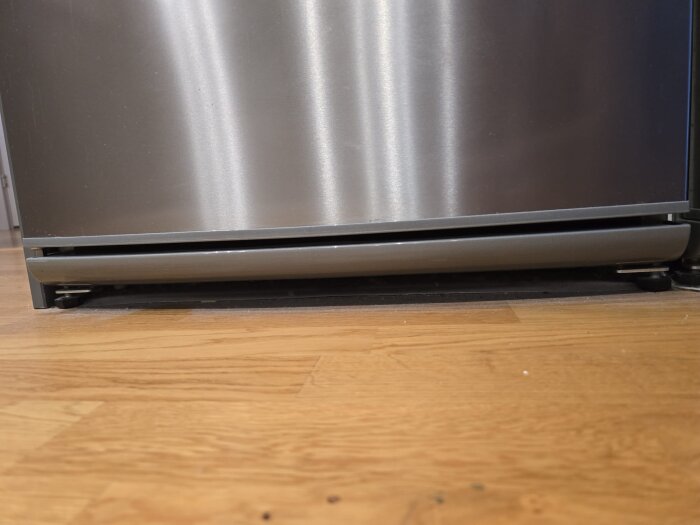 Kylskåpsdörrens gångjärn med synlig mutter som kan orsaka stängningsproblem.