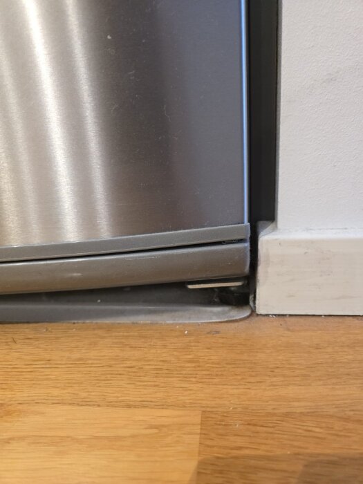 Kyldörr visar problem med gångjärn där en mutter verkar mindre synlig, vilket kan förhindra att dörren stängs automatiskt.