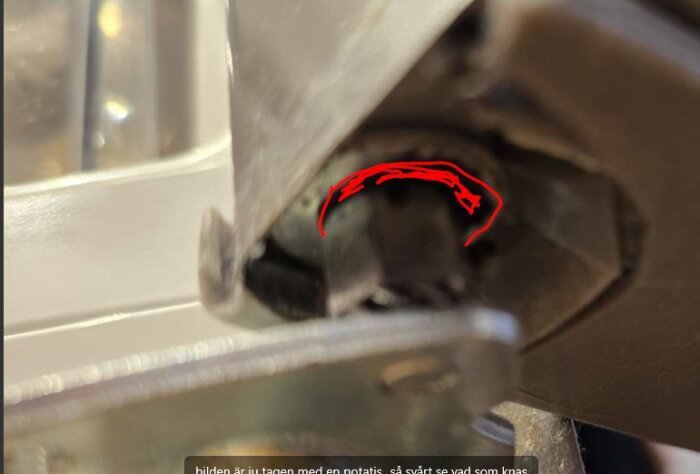 Närbild av en metallkomponent med en markerad spricka eller bruten del i rött, antyder möjlig skada.