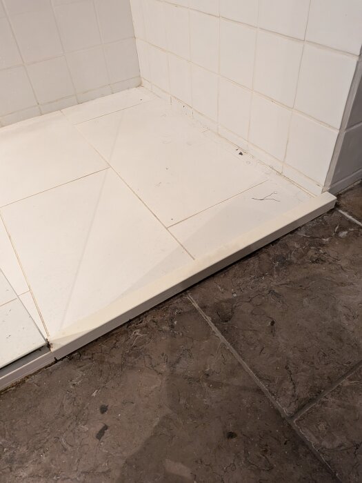 Bild av duschgolv med vit list och silikon, lösning för att förhindra läckage där kakel möter duschens golv.