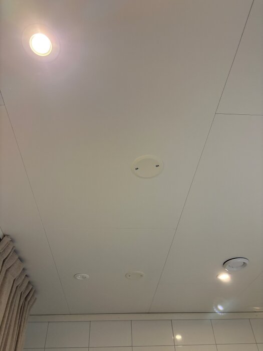 Tak i badrum med inbyggda spotlights, en lyser och en är urkopplad.