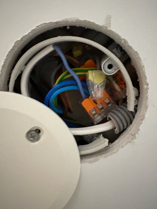 Kablage och kopplingar i en infälld elbox med flera färgglada ledningar och anslutningar synliga.