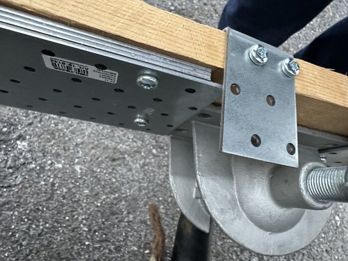 Träbit med fastskruvad hålplatta och vinkeljärn, bergt i metallfäste.