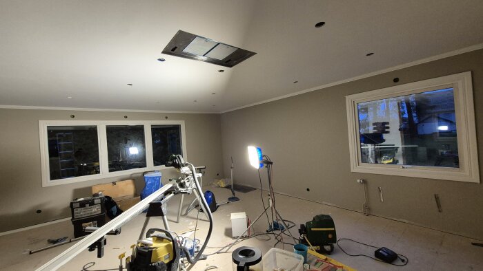 Rum under renovering med nymålade väggar, verktyg på golvet och takbelysning. Färdigställande av foder, med element som ska installeras.