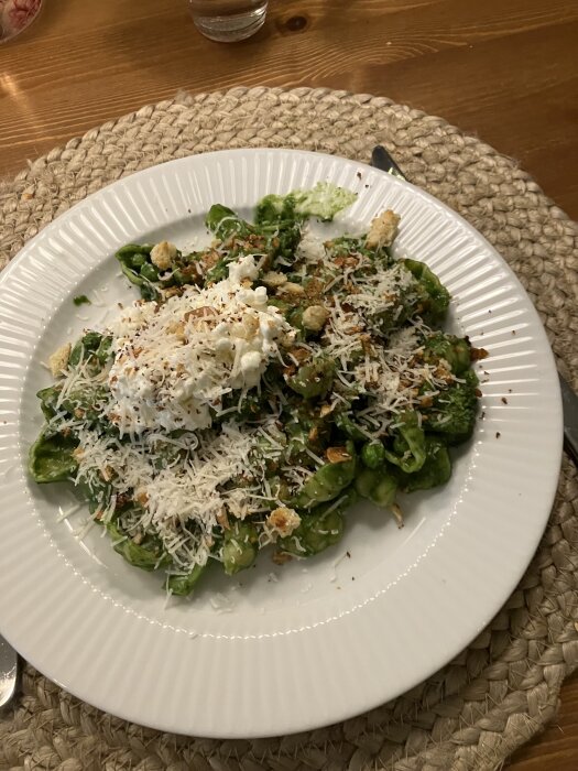 Pasta med broccoli och ärtor på tallrik, toppad med keso, parmesan och rostade brödsmulor.
