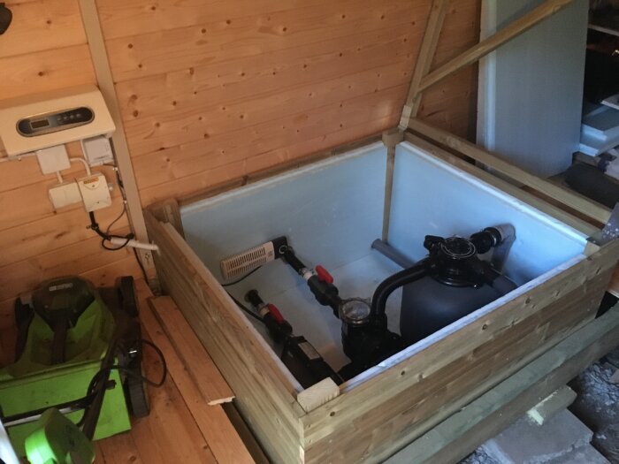 Isolerad låda med pump och manövrering i träklädd friggebod.