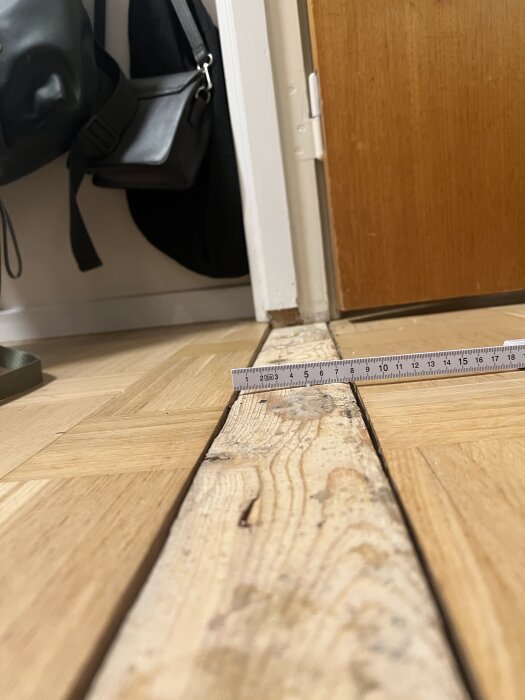 Sned tröskel med ojämn yta och en linjal placerad ovanpå, visar skillnaden i höjd mellan två golvytor.