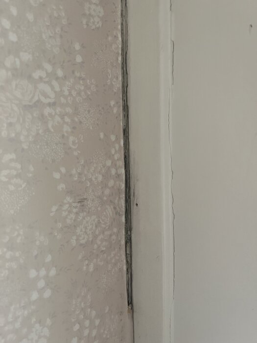 Spricka mellan tapetserad köksvägg och fönsterkarm, med otillräcklig tätning.