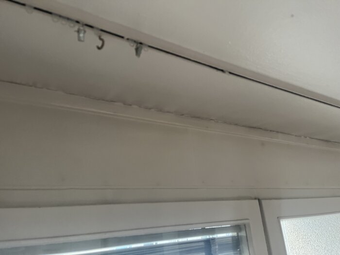 Ovanför köksfönstret avslöjar bilden en dåligt tätad kant med springor, vilket kan orsaka drag.