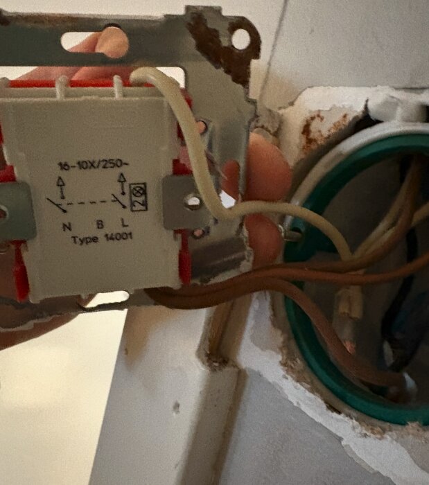 Tvåpolig strömbrytare med ledningar synliga bakom en vit vägg, märkt "16-10X/250 N B L Type 14001".