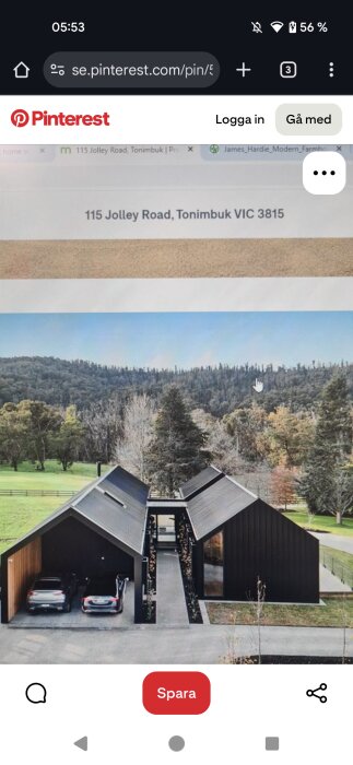 Modern villa med svart fasad och två parallella byggnader, omgiven av skog och landskap. En uppfart med bilar syns i förgrunden.