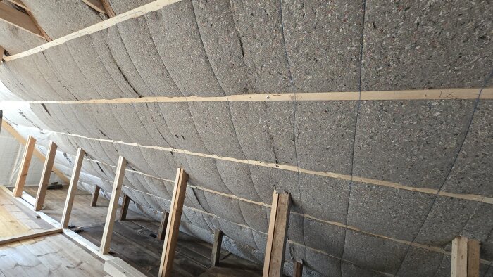Isolering av vägg med träreglar och skivor i ett pågående byggprojekt.