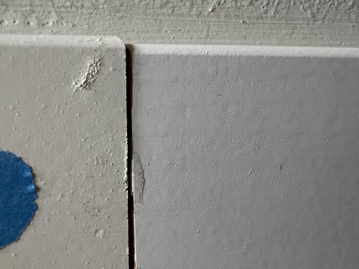 Glipa mellan två golvsocklar med olika färgnyanser, där en liten färgskillnad och en blå markering syns tydligt på vänstra sockeln.