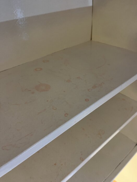 Vitmålat köksskåp med röda fläckar som tränger igenom färgen.