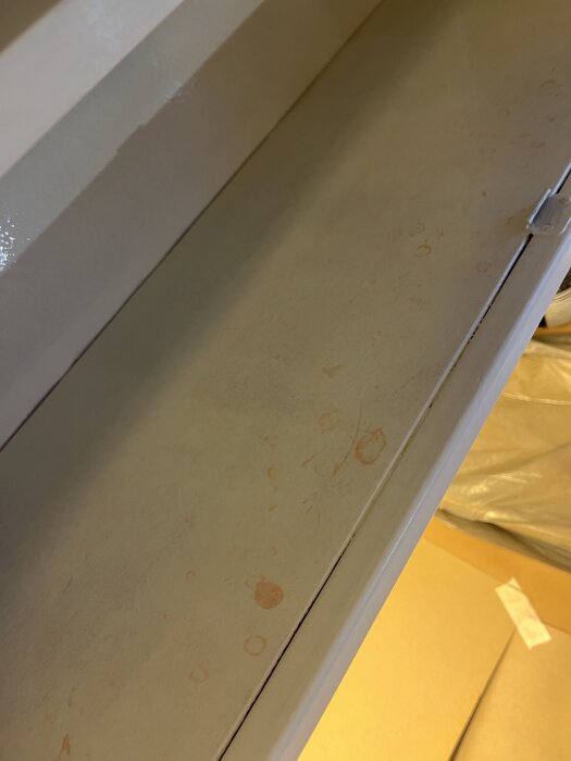 Vitt målat köksskåp med röda fläckar synliga under färgen, troligen genomträngande från tidigare röd målning.