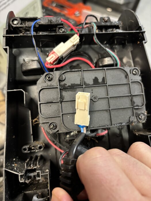 En närbild av ett elektriskt kontaktdon i en apparat med flera färgade kablar, där ordet "AMP" syns på kontaktdonet.