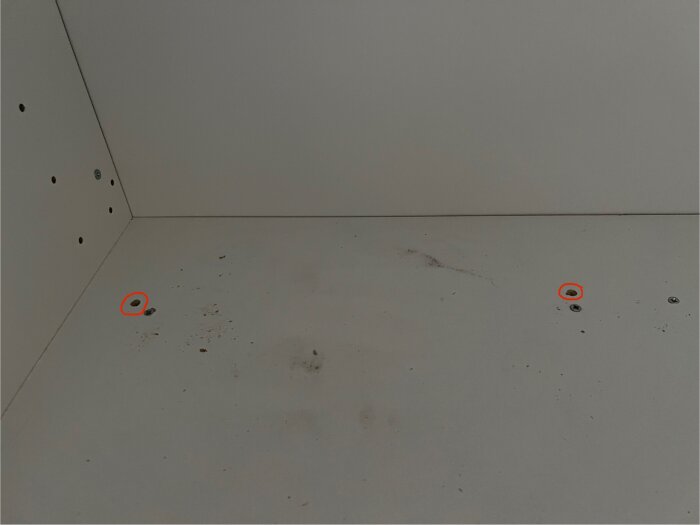 Sönderskruvat väggskåp med flera hål utan skruvar synliga, märkt med cirklar på vissa punkter, antyder ett renoveringsprojekt.