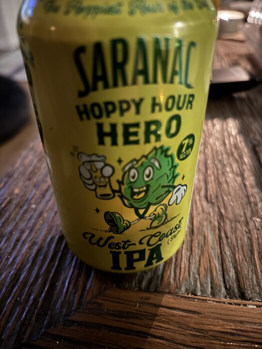 En burk Saranac Hoppy Hour Hero West Coast IPA med 7% alkohol, placerad på ett träbord.