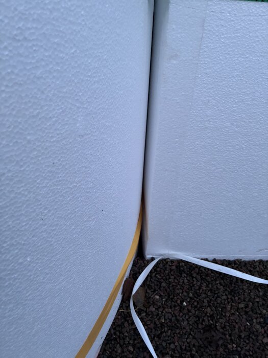 Glipa mellan isoleringspaneler i terrasspoolinstallation, med synlig frigolit och grus på marken.