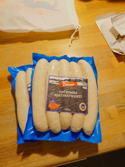 Förpackning med tyska Thüringer Rostbratwurst av märket Dulano på ett träbord.