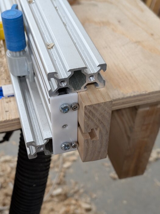 Aluminiumextrusion med trä och 3D-utskrivna komponenter monterade med skruvar, del av justerbart fräsbordsanhåll.