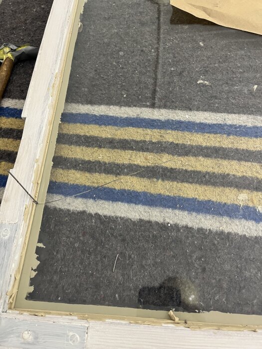 Sprucken glasruta efter att ha hamrats, med stifthammare synlig bredvid ramen.