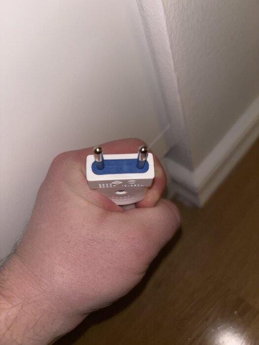 Hand holds a two-pin European plug with blue and white details against a wall, questioning compatibility with a Plejd SPD-01.