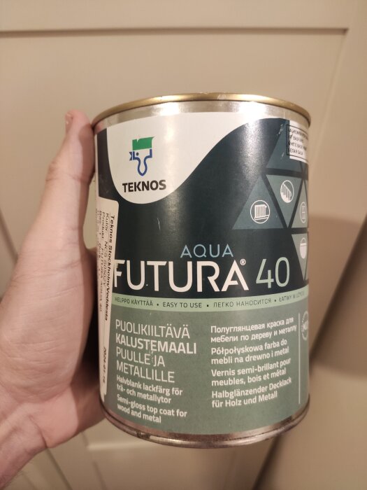 En burk halvblank lackfärg märkt "TEKNOS Aqua Futura 40", lämplig för trä och metall, hålls i en hand.