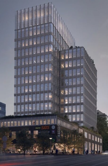 En modern kontorsbyggnad med glasfasad och upplysta fönster, omgiven av träd.