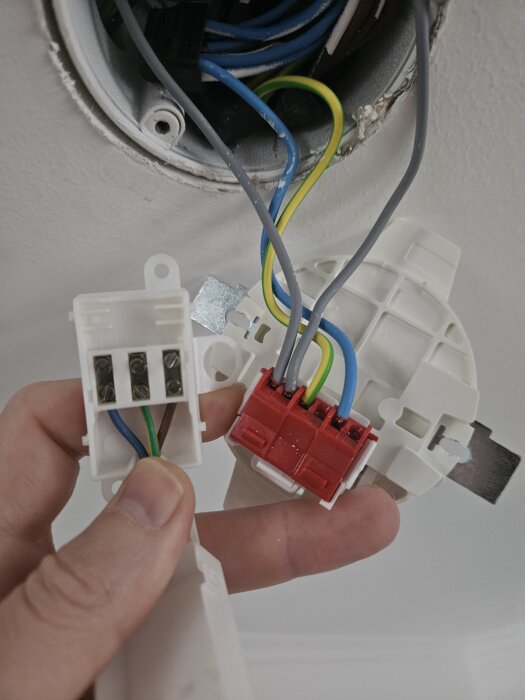 Elektrisk anslutning med flera färgade ledningar från taket och en lampa, inklusive en kopplingsdosa och kontakter.