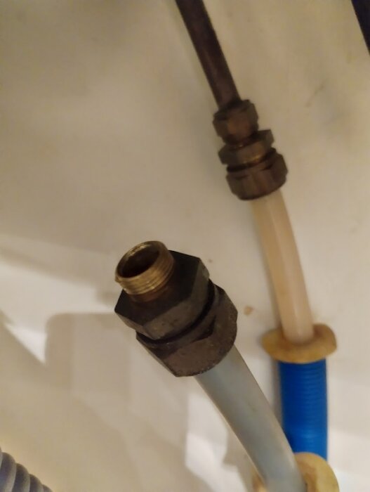 Under vasken med anslutningar för vattenrör, visar en metallfattning som behöver en övergång från 15 mm till 10 mm med gummipackning.