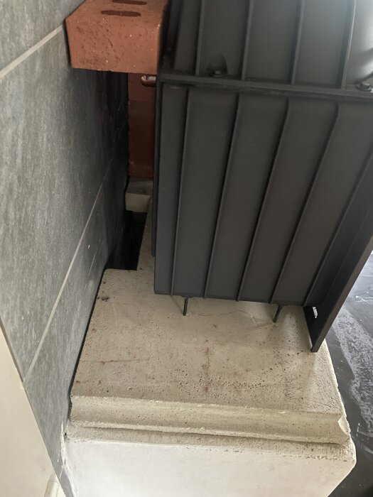 Murad eldstad med insatskamin integrerad i rummet, visar del av konstruktionen med tegel och betong.